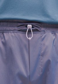 Lyse lilla atletiske shorts med elastisk talje og hvid snor. Stoffet har et subtilt rutemønster og en glat tekstur.