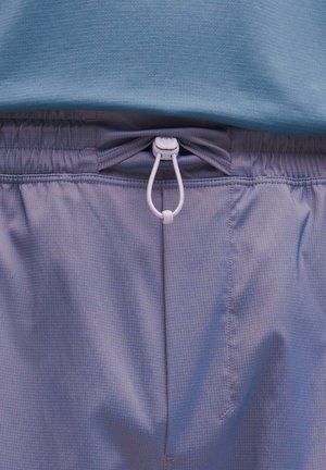 Pantaloni sportivi di colore viola chiaro con cintura elastica e stringa bianca. Il tessuto presenta un sottile motivo a rete, con una consistenza liscia.