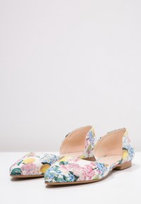 Chaussures plates fleuries à bout pointu ; présentent un imprimé coloré de fleurs roses et bleues sur fond blanc avec une conception à côté ouvert.