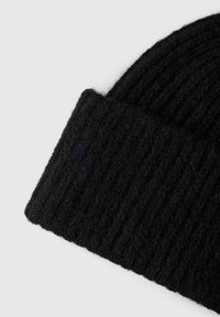 Beanie nero in maglia con una texture a coste, caratterizzato da un risvolto. Il materiale sembra morbido e leggermente peloso, indicando calore.