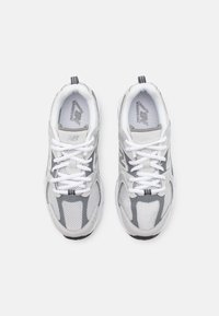 Witte en grijze sport schoenen met gaaspanelen, dikke zolen en ronde veters. Merklogo zichtbaar op de tong en zijkanten.