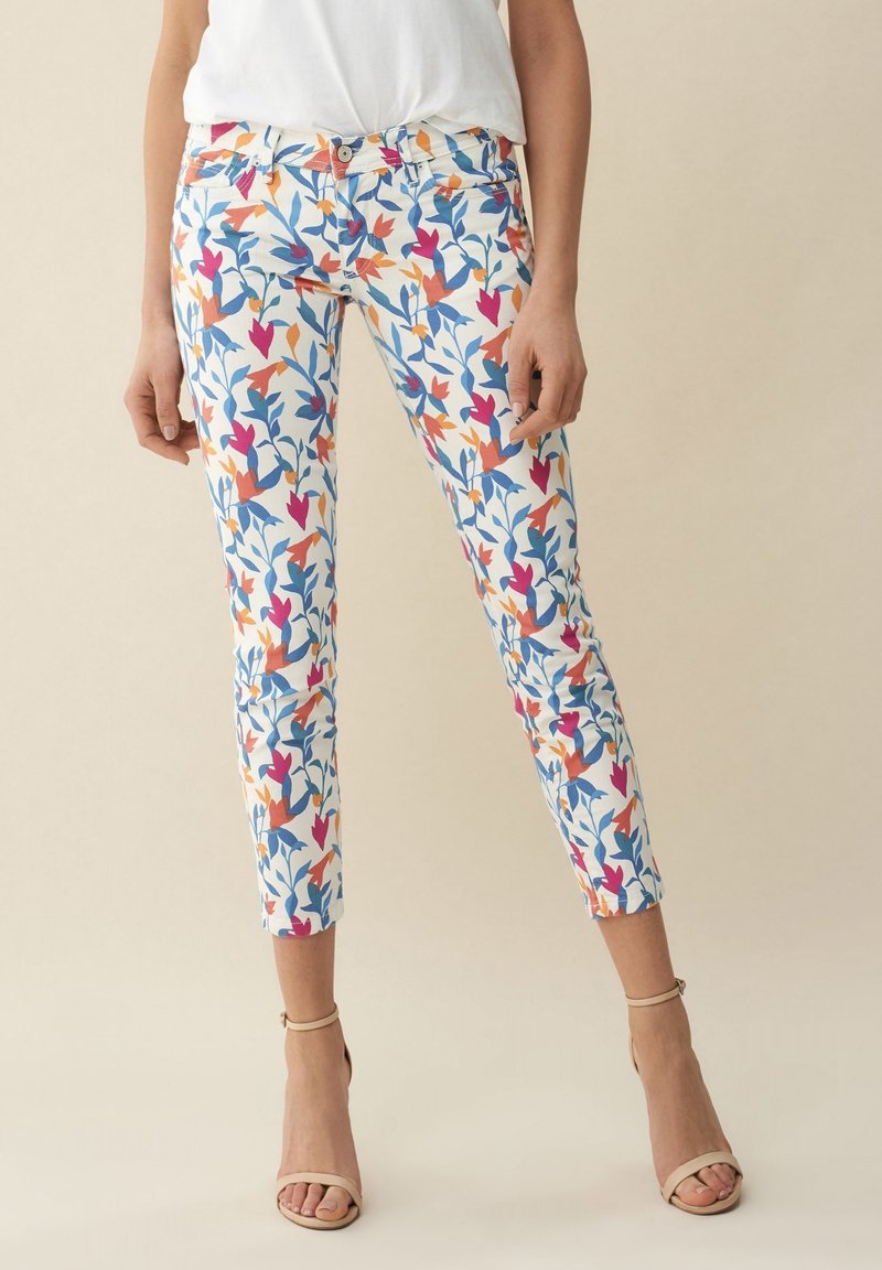 Dámské džíny s květinovým vzorem v bílé barvě s modrými, oranžovými a růžovými listovými designy. Tvarovaný střih s středním pasem a délka po kotníky.