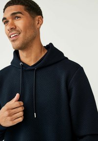 Marine hoodie met een gestructureerd patroon, verstelbare trekkoord en een kangoeroezak. Zacht materiaal met een ontspannen pasvorm, met een kraagontwerp.