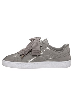 Błyszczące szare tenisówki z dużymi, teksturowanymi sznurowadłami zawiązanymi w dużą kokardę, biała podeszwa i niskim krojem.