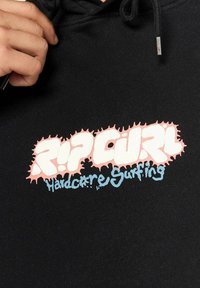 Hoodie noir avec un graphisme prominent contenant un texte rose et bleu "RIP CURL Hardcore Surfing", agrémenté d'accents de taches colorées.