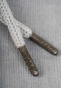 Grey braided shoelaces with metal aglets inscribed "Reell," featuring a smooth texture and rounded tips.