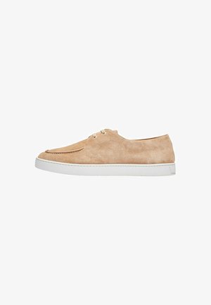 Sænkede casual sko i beige i ruskind med en lav profil, hvid gummisål og minimalistisk snøring. Tekstureret overdel med stikninger.