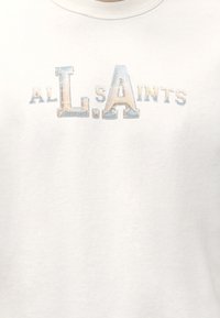 Λευκό t-shirt με στρογγυλή λαιμόκοψη με ξεθωριασμένο, πολύχρωμο κείμενο που γράφει "ALL SAINTS" με έμφαση στα μεγάλα γράμματα "L" και "A" στο κέντρο.
