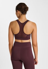 Bordeaux sportbeha met een racerback-ontwerp, gladde stof en brede bandjes. Gecombineerd met bijpassende leggings met hoge taille.