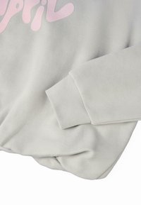 Sudadera de color gris claro con puños acanalados, textura suave y corte holgado, con el diseño del texto "Abril" en rosa en la parte delantera.
