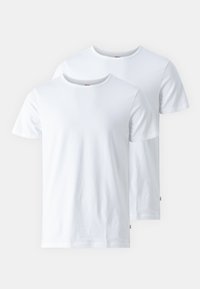 Deux t-shirts en coton blancs avec un col rond, des manches courtes et une texture lisse ; un t-shirt légèrement superposé derrière l'autre.