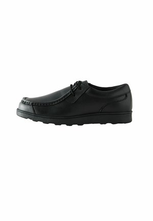 Chaussure en cuir noir avec un bout arrondi, des coutures discrètes et un minimum de détails de lacets. Semelle en caoutchouc flexible. Texture lisse en totalité.