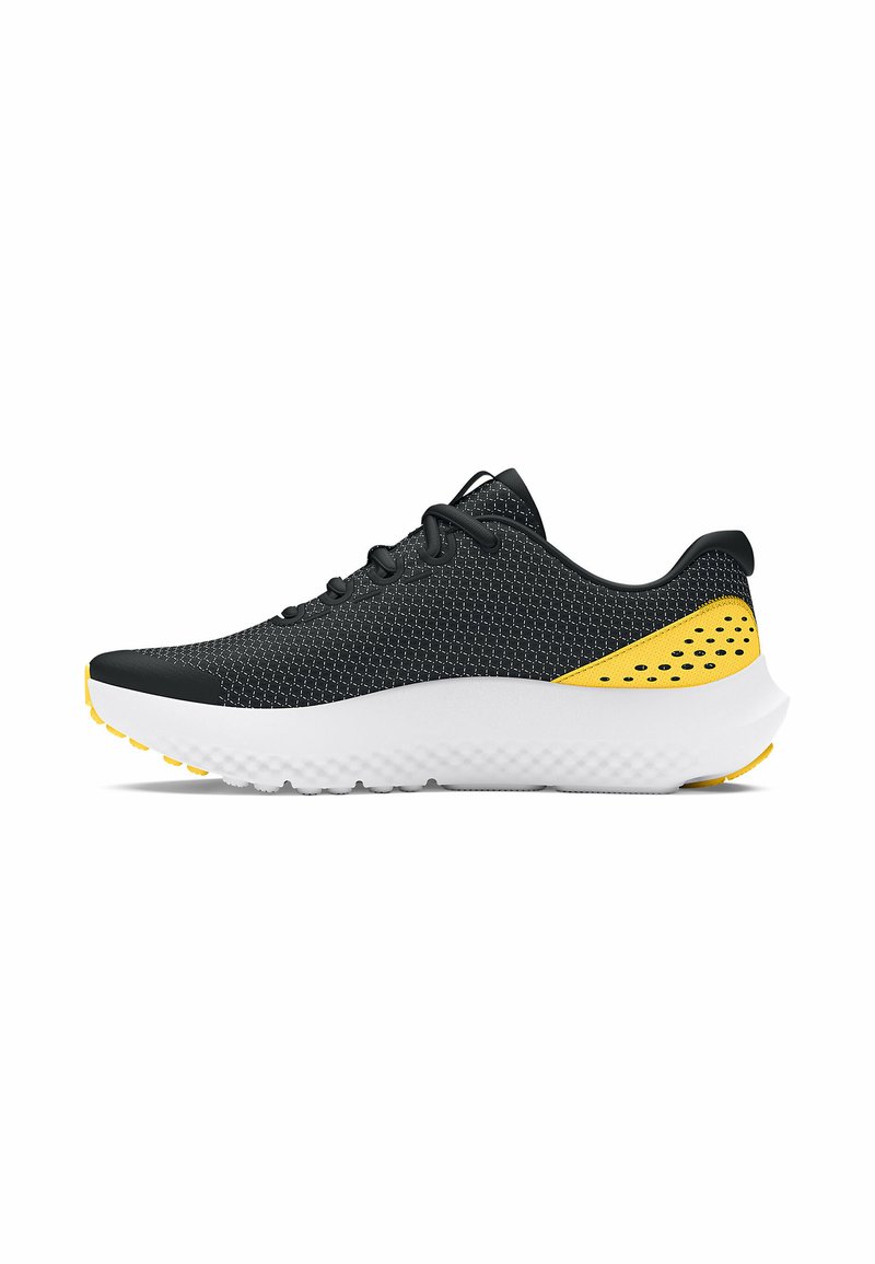 Chaussure de sport en mesh noir avec des accents jaunes, une semelle blanche texturée, un bout arrondi et six œillets pour les lacets. Présente des trous de ventilation sur les côtés.