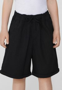 Černé bavlněné šortky s elastickým pasem, detaily na stáhnutí, a ohrnutými manžetami, s uvolněným střihem a bočními kapsami.