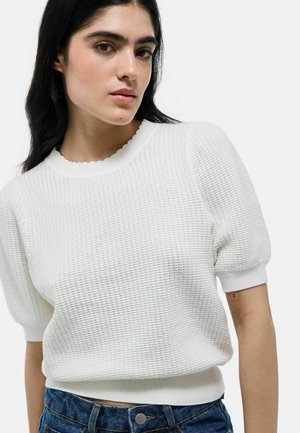 Pull blanc texturé avec un col festonné et des manches courtes bouffantes, associé à un short en denim taille haute avec un accent de bouton.