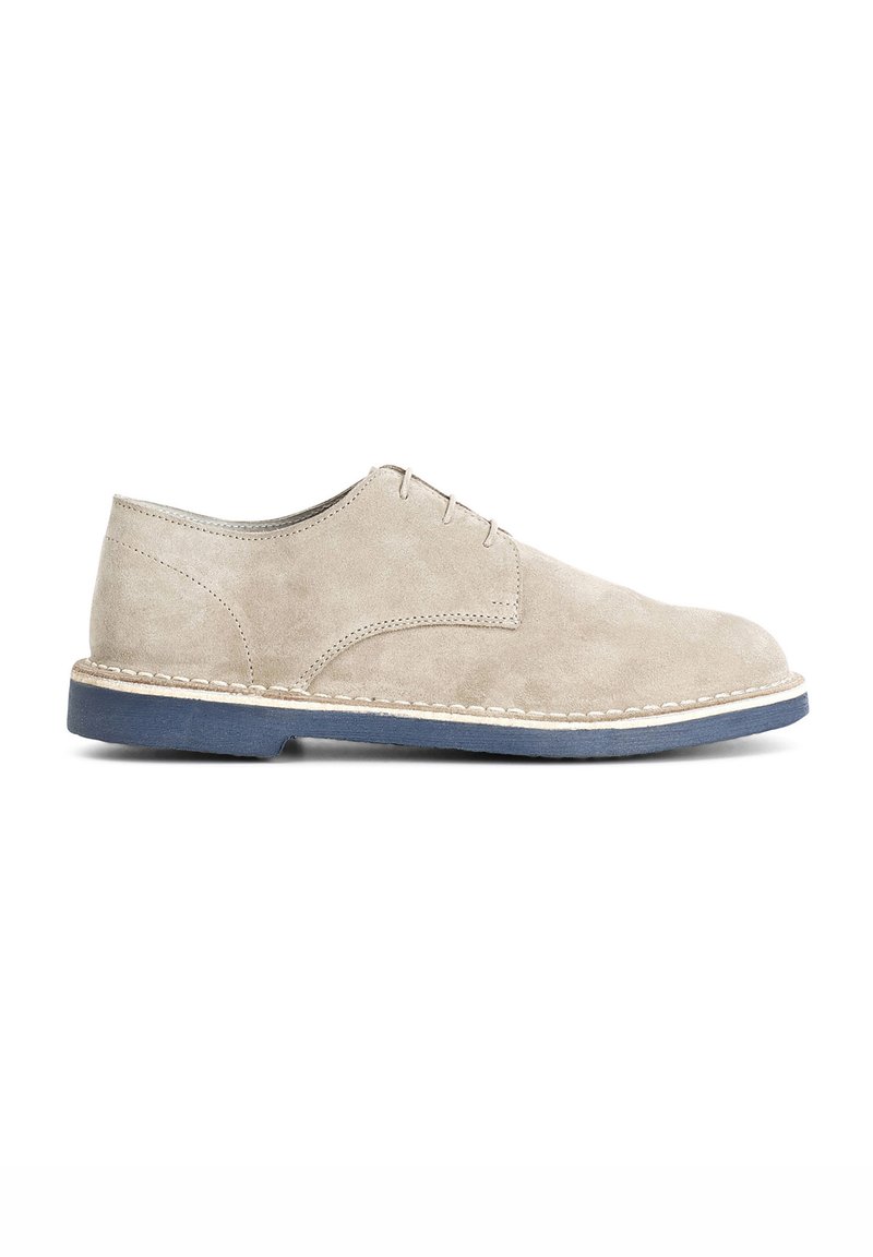 Scarpe in suede beige con punta rotonda, caratterizzate da un semplice design con lacci e una suola blu a contrasto con cuciture lungo il bordo.