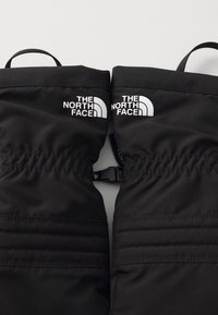 Luvas isoladas pretas da The North Face com um tecido texturizado, punhos elásticos e logo impresso em branco. Apresenta um fecho tipo clip.