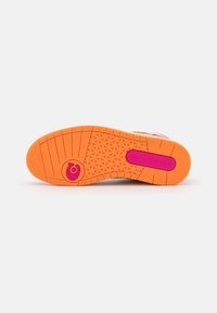 Sole boty v jasně oranžové gumě s texturovaným vzorem a růžovými akcenty. Obsahuje kruhové logo a plochý design pro stabilitu.