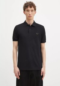 Polo shirt nero in cotone con colletto, patta con due bottoni e logo ricamato sul lato sinistro del petto. Maniche corte e tessuto testurizzato.