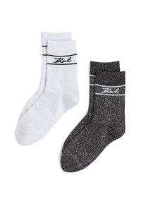 Deux paires de chaussettes : une paire gris clair avec des rayures noires et un logo, l'autre noire avec un motif texturé et des rayures blanches près du haut.