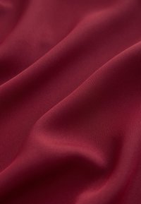 Dybrødt stof med en glat tekstur, der har et subtilt ribbet mønster og bløde draperingsegenskaber.