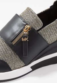 Zwarte sneaker met een glanzende, geweven bovenkant featuring metalen draad. Inclusief een decoratieve gouden rits en merklabel. Witte en zwarte buitenzool.