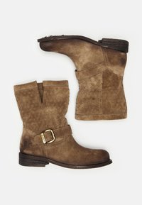 Botas de tobillo de ante en marrón claro con un patrón trenzado, acento de hebilla dorada y un tacón bajo. Parte superior texturizada con un acabado ligeramente usado.