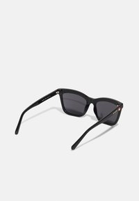 Black sunglasses with a glossy finish, angular frames, dark lenses, and slender arms featuring a logo and accent detail on one side.