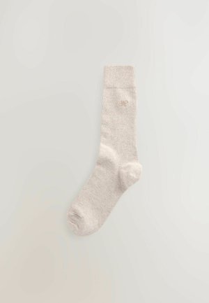 Calzino in cotone beige con risvolto a coste, caratterizzato da un piccolo logo ricamato vicino alla caviglia. Tessuto morbido, design alla caviglia.