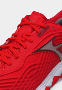 Φωτεινό κόκκινο αθλητικό παπούτσι με κόκκινα κορδόνια, υφασμένο επάνω μέρος, ασημένια λογότυπο και λευκή και κόκκινη σχεδιασμένη σόλα.