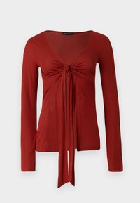 Κόκκινο μακρυμάνικο τοπ με βαθύ V-λαιμόκοψη, σούρες μπροστά και δετό φιόγκο στη μέση· κατασκευασμένο από μαλακό, ελαστικό ύφασμα.