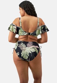 Mustat bikinit, joissa on olkapäiltä roikkuva frill ja trooppinen lehtikuvio vihreänä ja vaaleanpunaisena. Sivuilla solmittavat remmit säädettävää istuvuutta varten.