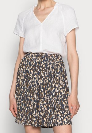 Valkoinen lyhythihainen V-kaula-aukollinen pusero, jonka kanssa on laskostettu, korkeavyötäröinen hame, jossa on tummansininen, beige ja ruskea abstrakti kuvio.