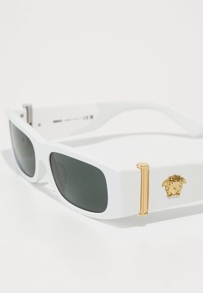 Lunettes de soleil blanches avec des verres gris rectangulaires, accent en métal doré, arborant un emblème de Méduse sur le côté et une finition brillante.