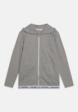 Grauer Hoodie mit durchgehendem Reißverschluss, Fronttaschen, langen Ärmeln, Kapuze und weißem Saumband mit dem aufgedruckten "Calvin Klein"-Logo.