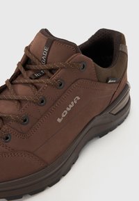 Bruine wandelschoenen gemaakt van suede en mesh, met een vetersluiting, logo aan de zijkant en een rubberen zool met textuur en dempende accenten.