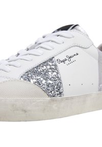 Baskets blanches avec panneau pailleté argenté, lacets blancs, embout beige et logo "Pepe Jeans London" sur le côté. Semelle usée et texturée visible.