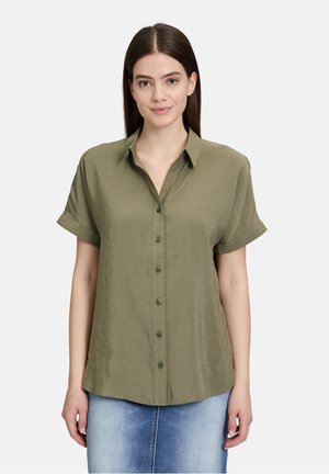 Chemise olive verte à manches courtes avec boutonnière, dotée d'un col, d'un tissu doux et texturé, et d'une coupe ample avec un ourlet arrondi.
