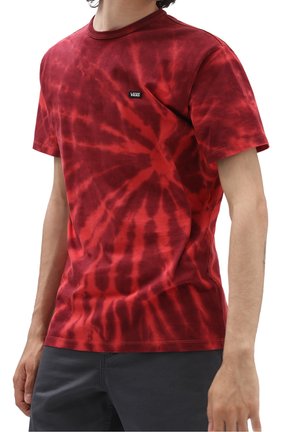 Person, der ein rot gefärbtes Vans-T-Shirt mit kurzen Ärmeln und dunklen Hosen trägt, von Hals bis zu den Oberschenkeln dargestellt.