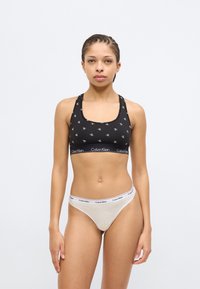 Μαύρο αθλητικό σουτιέν με το μοτίβο λογοτύπου CK, με τετράγωνο ντεκολτέ και φαρδιές τιράντες, συνδυασμένο με ανοιχτόχρωμο στρινγκ με ελαστική ζώνη.