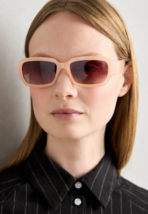 Lyserøde solbriller med firkantet stel, mørke gradientlinser og en glat finish, parret med en sort stribet skjorte.