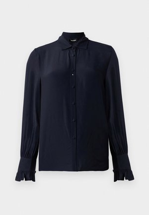 Mørkeblå bluse laget av glatt stoff, med spiss krage, knappefront og volangmansjetter. Lange ermer med lett gathering.
