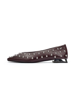 Zapato plano de cuero burdeos con punta afilada, adornado con clavos de metal plateado y un tacón metálico bajo para apoyo y estabilidad.