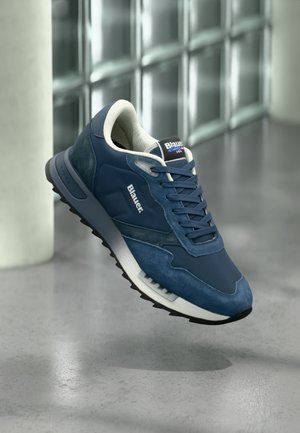 Scarpa sportiva blu con design in materiali misti che includono suede e mesh, punta rotonda, dettagli bianchi e suola nera testurizzata.