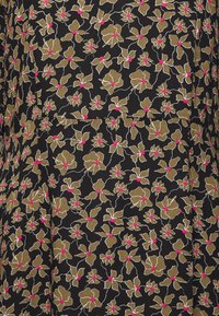 Svart tyg med ett blommönster av guld och vita blommor med rosa mittar, som visar upp intrikata detaljer och en jämn textur.