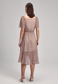 Midikleid mit Blumenmuster und Puffärmeln. Leichter Stoff mit pinken und grünen geometrischen Designs. Figurnaher Taillenbereich mit ausgestellt geschnittenem Saum.