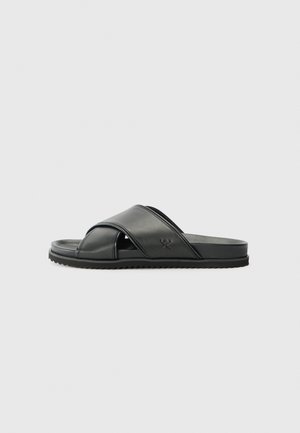Black slide sandal with crossed straps, made of smooth synthetic material. Features a textured outsole for grip. Simple design, no embellishments.