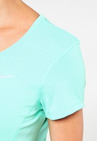 Camiseta deportiva ligera en verde menta con una tela texturizada y transpirable. Presenta un cuello redondo y mangas cortas con un sutil patrón de puntos.
