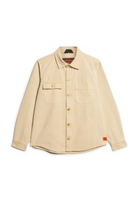 Camisa beige de botones hecha de algodón, con cuello, dos bolsillos en el pecho y botones en tono dorado. Presenta una etiqueta de marca en el dobladillo.