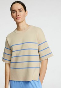 Maglietta beige a maniche corte con strisce orizzontali blu. Caratterizzata da un colletto rotondo e una vestibilità leggermente ampia con orlo dritto.